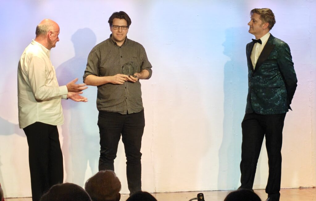 Director P Wintle on stage with adjudicator Trastan Marshall and Rod CHaytor at the awarding of the trophy